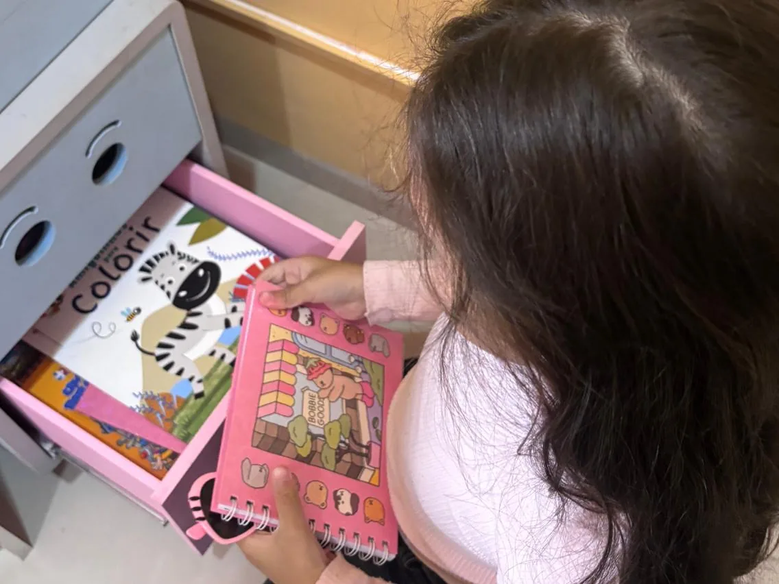 Criança escolhendo um livro de colorir na gaveta do consultório